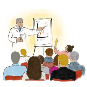 Ein Mann in weißem Arztkittel spricht vor einer Gruppe von Menschen. Er zeigt mit einem Stift auf eine Verlaufskurve, die auf dem Papier einer Flipchart zu sehen ist. Eine Teilnehmerin meldet sich.